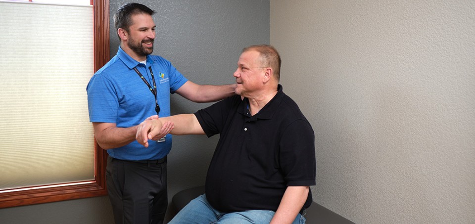 Doctor standing by a patient while examining his arm