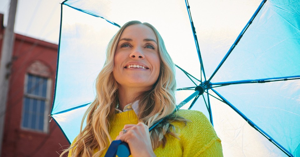 Woman with an umbrella looking up and smiling