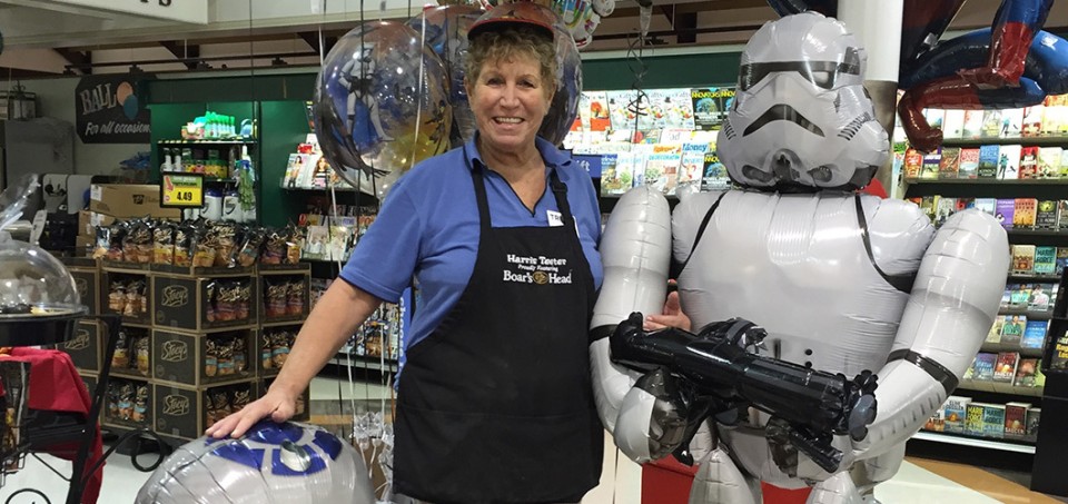 Woman with an apron standing in a toy store next to a robot