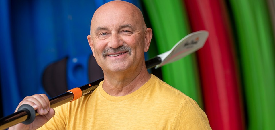 Man smiling with a kayak paddle over his shoulder