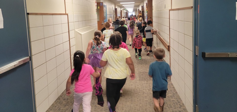 Children and teacher running in a school hallway