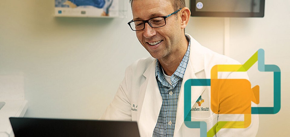 Doctor smiling while looking at his computer.