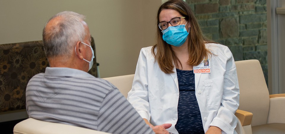 Doctor and patient with masks sitting in chairs facing each other