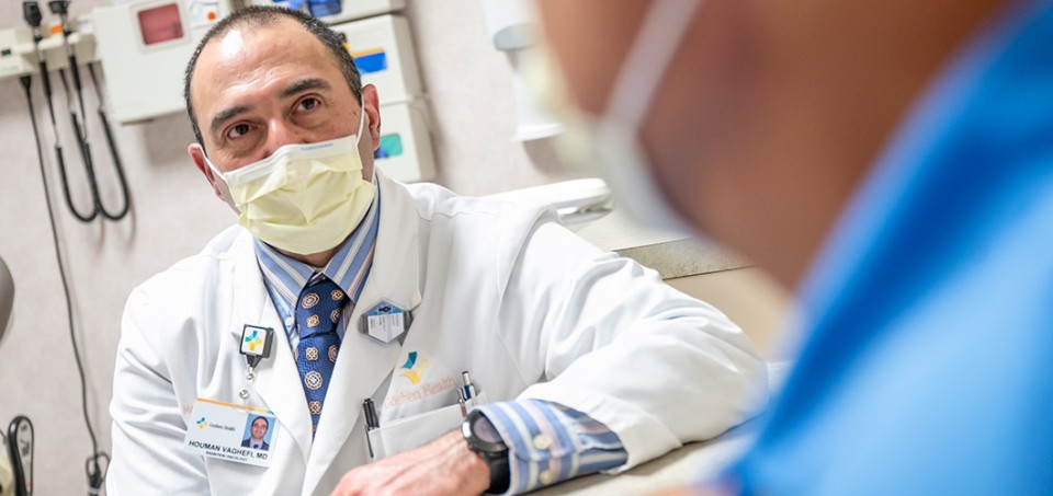 Doctor with a white coat and mask, talking to a patient