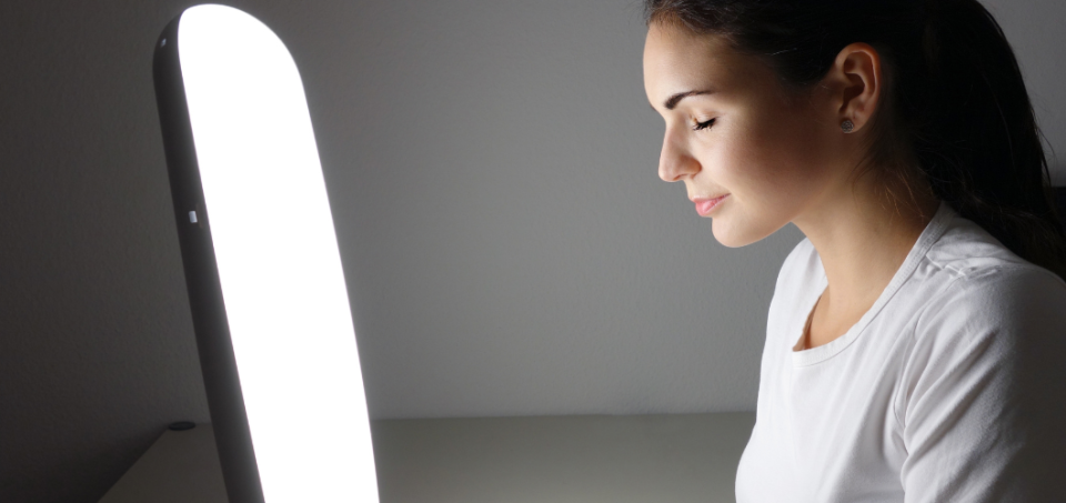 Woman sitting in front of a light therapy device
