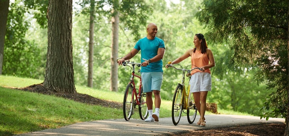 Couple talking while walking their bikes in a park