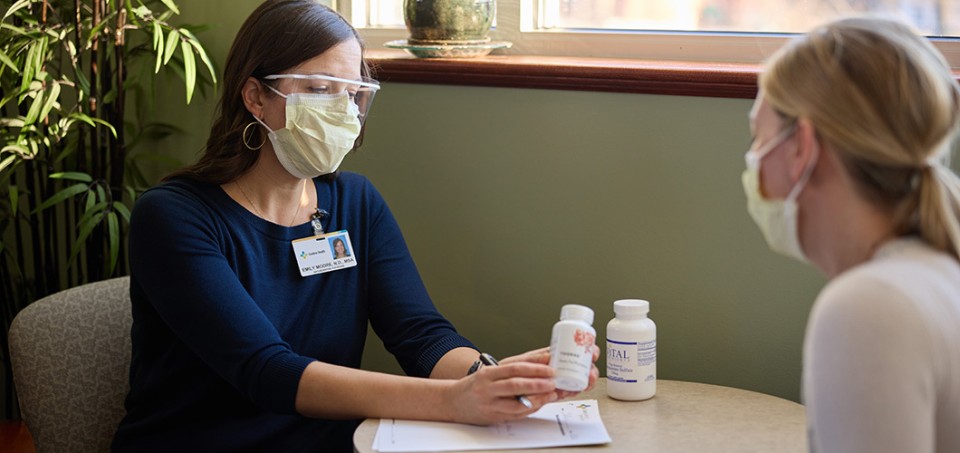 Two women sitting across from each other at a table with masks on