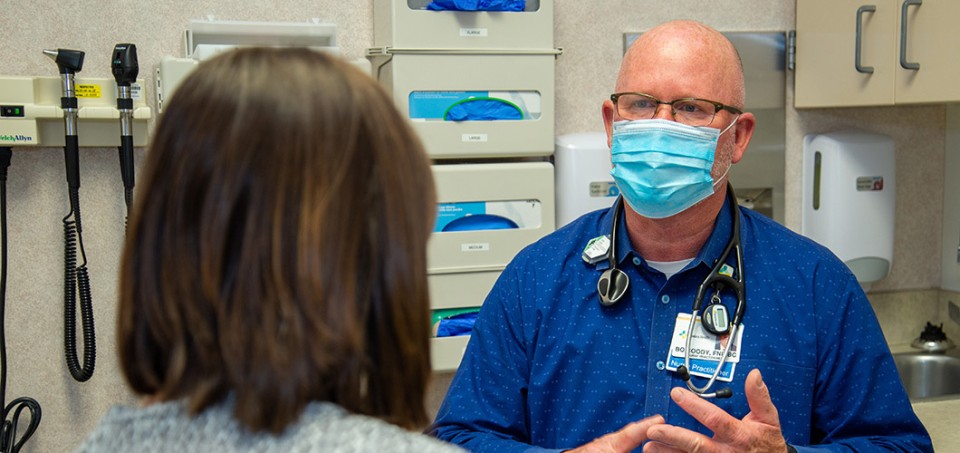 Doctor with stethoscope facing a patient in an examination room
