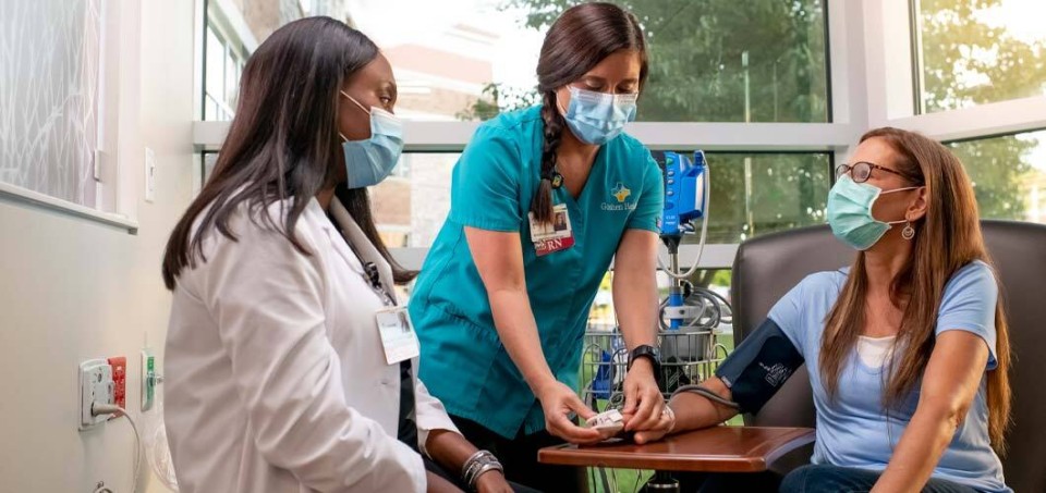 Two nurses sit with a patient getting a procedure