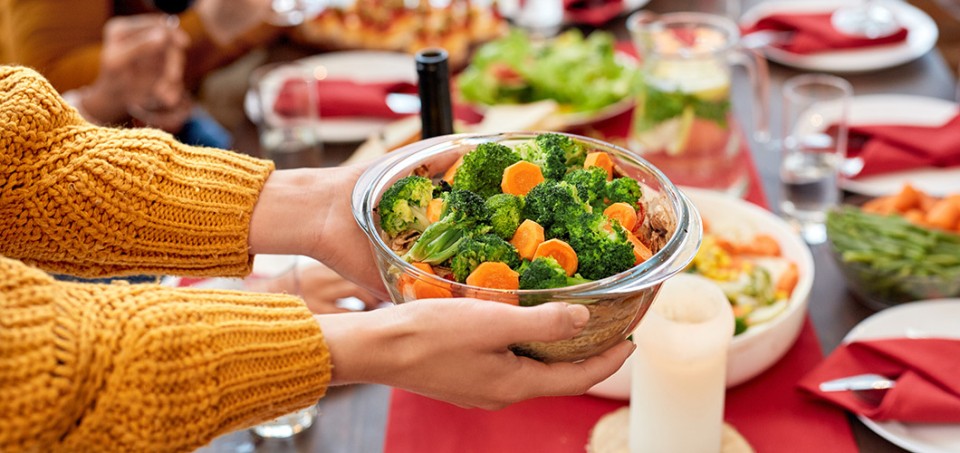 Hands placing a full salad bowl on a table full of food