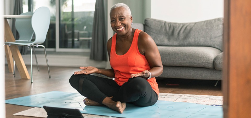 Older woman smiling while sitting on the floor in a yoga pose