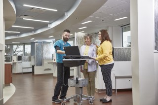 Three people standing around a computer