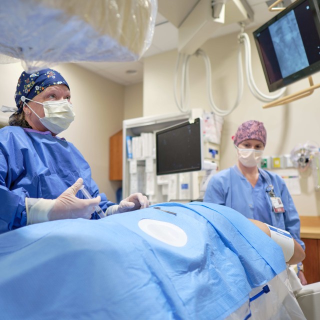 Doctor and nurse performing a procedure on a patient lying on a bed