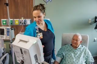 Nurse looking at a monitor while a patient is sitting in a chair