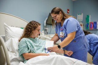 Nurse standing by a patient in a bed taking her blood pressure