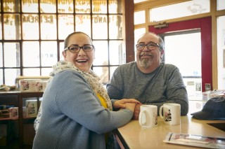 Couple smiling while sitting at a counter drinking coffee
