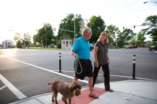 Man and woman walking their dog on the sidewalk