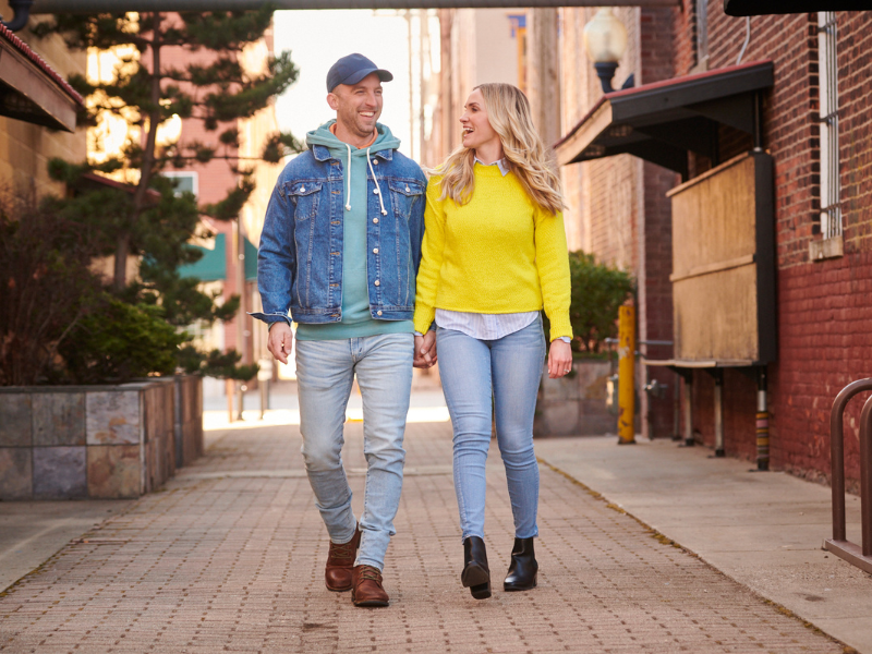 A couple holding hands and walking down an alley