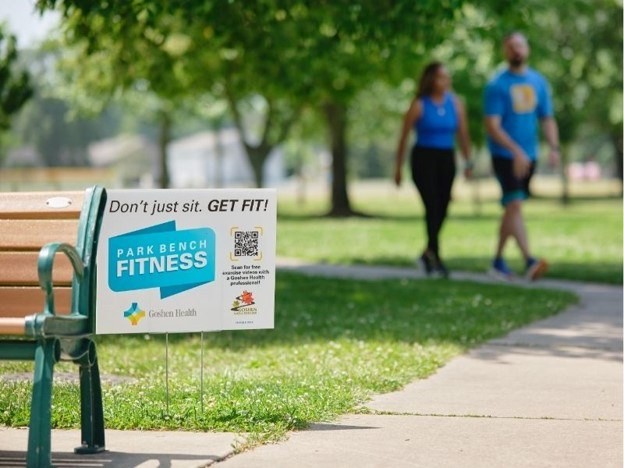 A couple walking on a park sidewalk approaching a bench