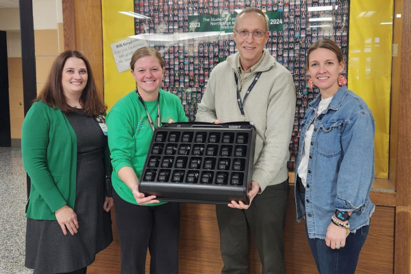 Four people handing together holding a heart rate monitor
