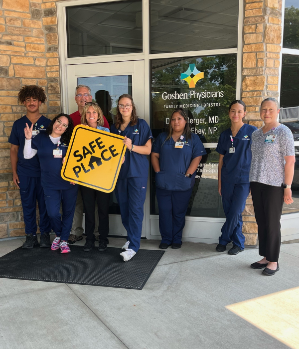 Doctors standing outside the building holding a sign that says, "Safe Place"