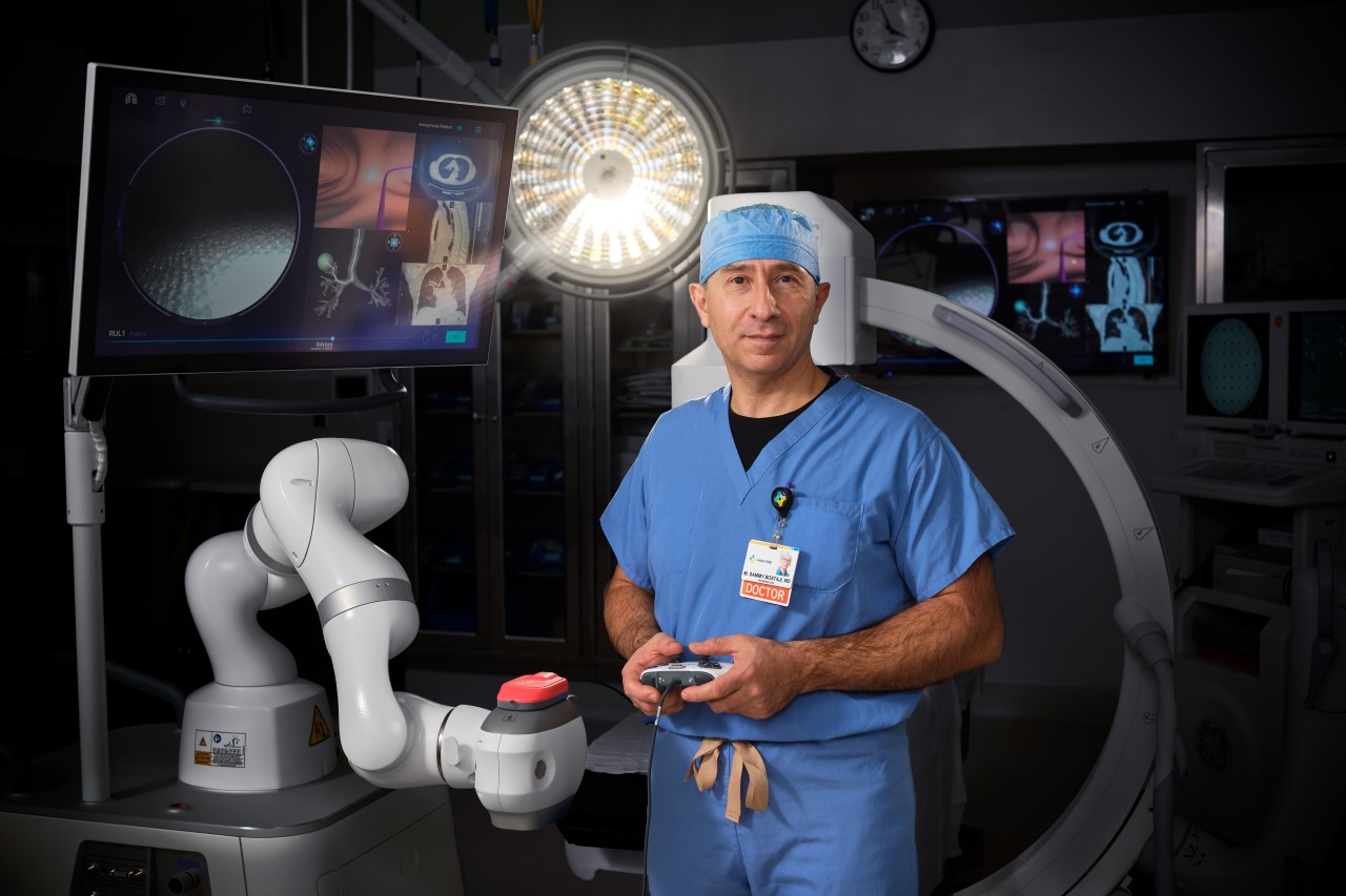 Doctor standing in front of a large medical device while holding controls