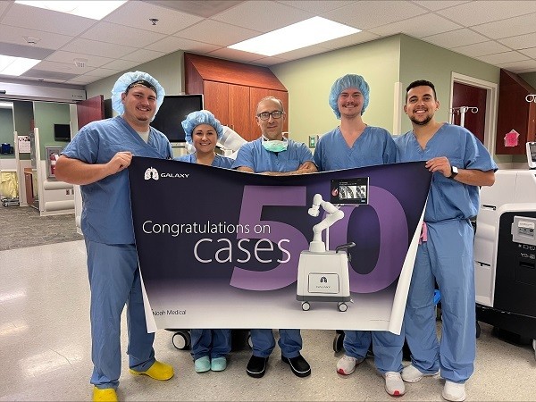 Doctors are standing shoulder to shoulder while holding a banner in a hospital