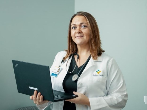 Nurse Practitioner wearing a lab coat while holding a computer
