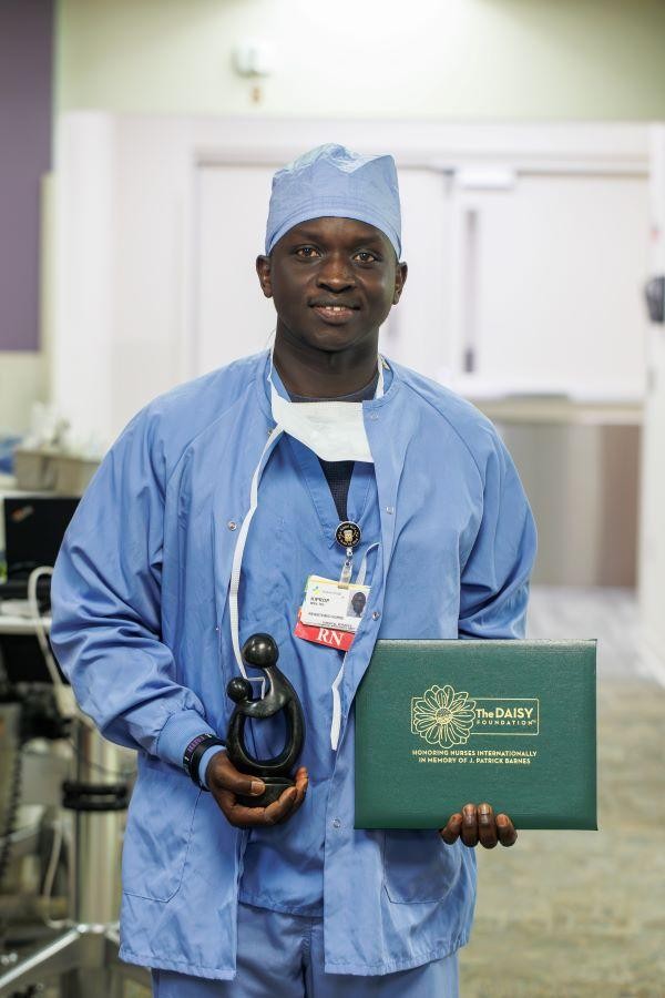 Nurse in scrubs holding an award