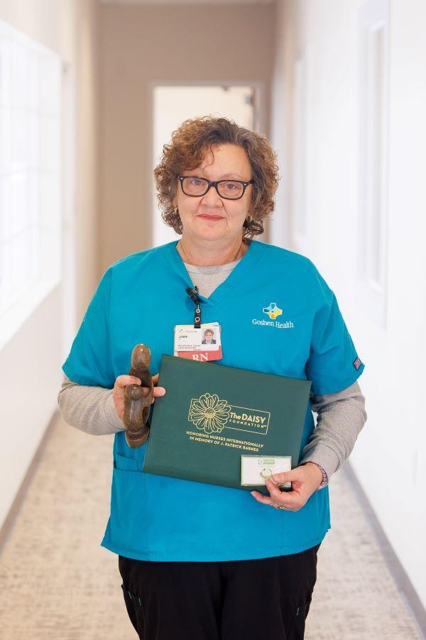 Woman standing in hallway holding an award