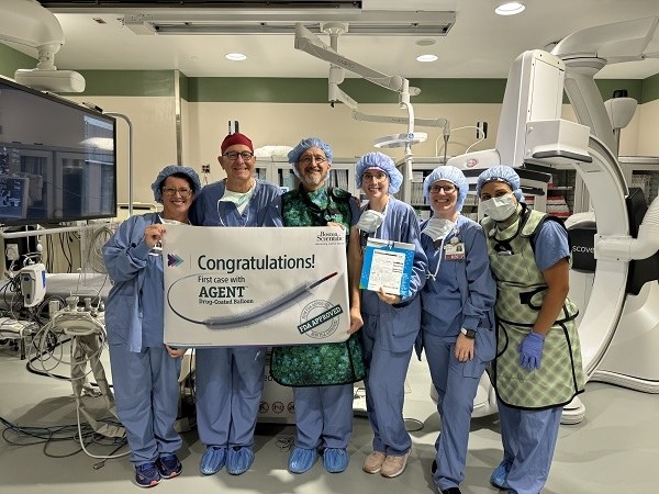 Doctors standing in front of a medical machine holding a banner