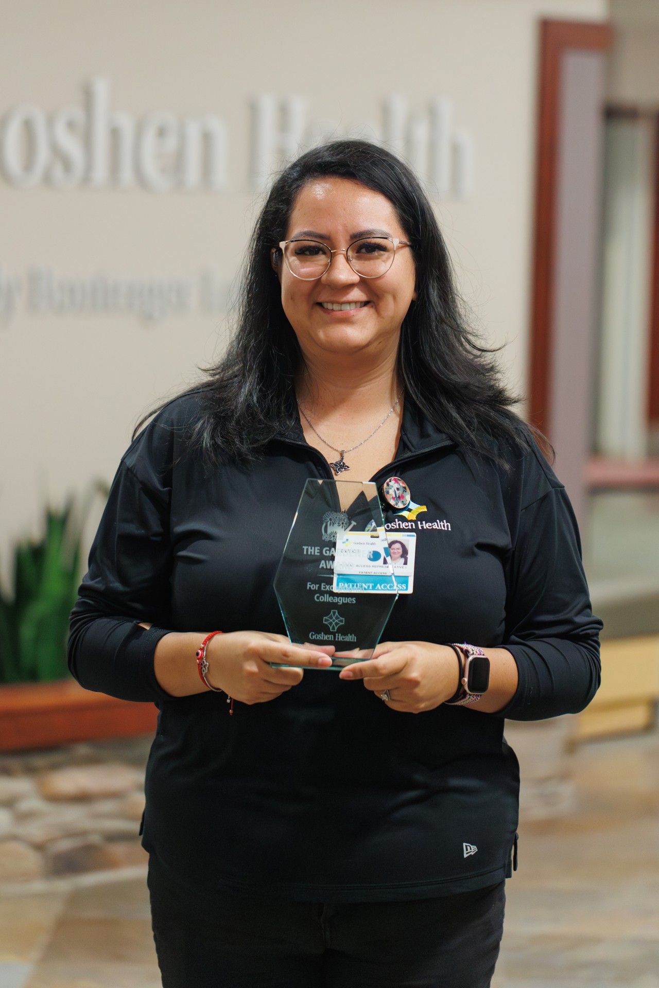 Smiling woman standing in front of a wall accepting an award