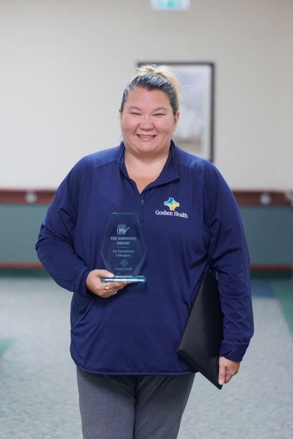 Smiling woman standing while holding a trophy