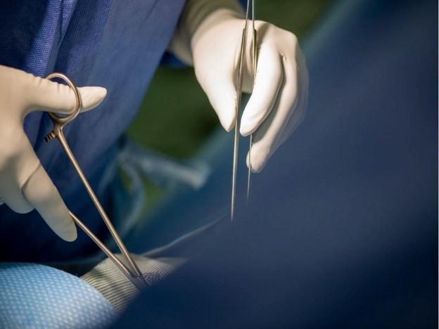 Two hands holding surgical instruments during a procedure