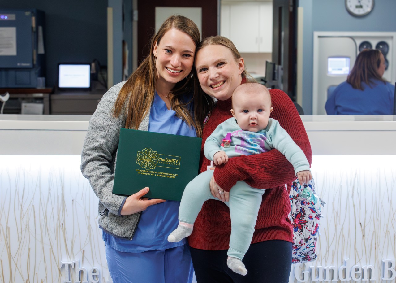 Two women holding a baby and an award