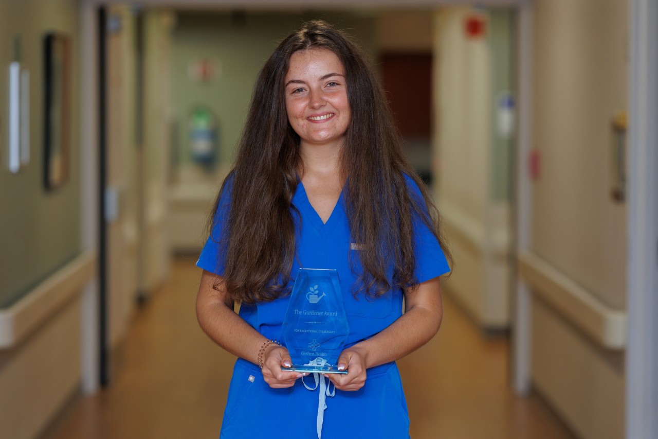 Woman with long hair smiling while holding an award