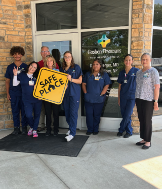 Doctors standing outside the building holding a sign that says, "Safe Place"
