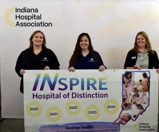 Three smiling women holding a banner that says, "Inspire, Hospital of Distinction"