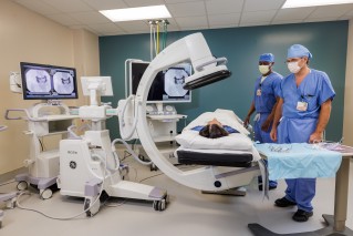Two doctors standing next to the bed of a patient getting a test