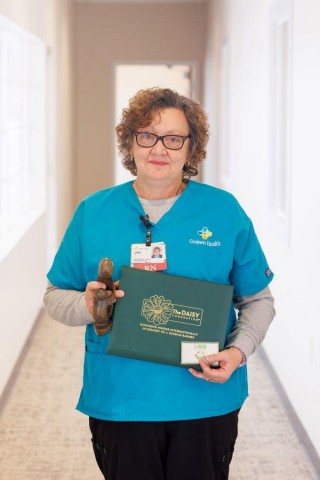 Woman standing in hallway holding an award