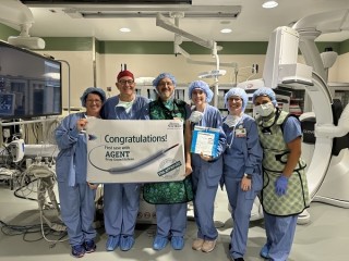 Doctors standing in front of a medical machine holding a banner