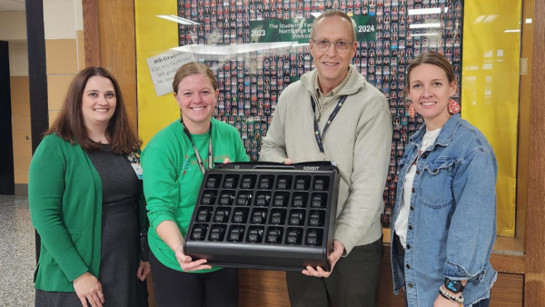 Four people handing together holding a heart rate monitor
