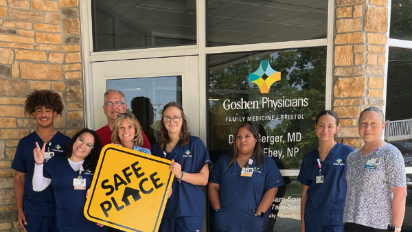 Doctors standing outside the building holding a sign that says, "Safe Place"