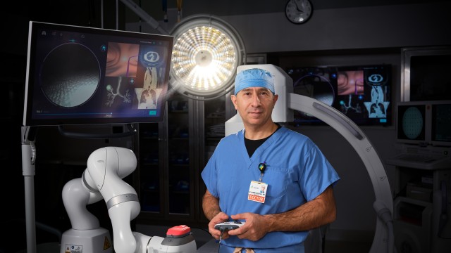 Doctor standing in front of a large medical device while holding controls