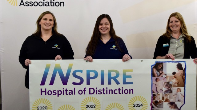Three smiling women holding a banner that says, "Inspire, Hospital of Distinction"