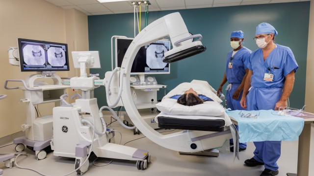 Two doctors standing next to the bed of a patient getting a test