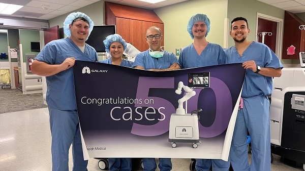 Doctors are standing shoulder to shoulder while holding a banner in a hospital