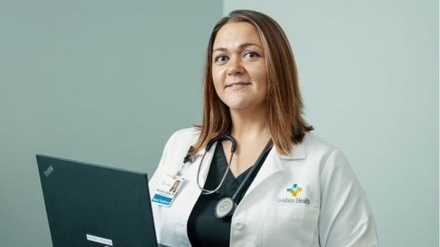 Nurse Practitioner wearing a lab coat while holding a computer