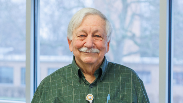 Older man smiling while holding an award
