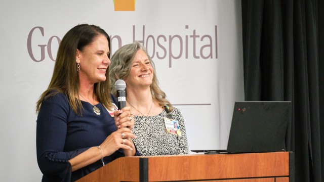 Two women standing at a podium with a microphone
